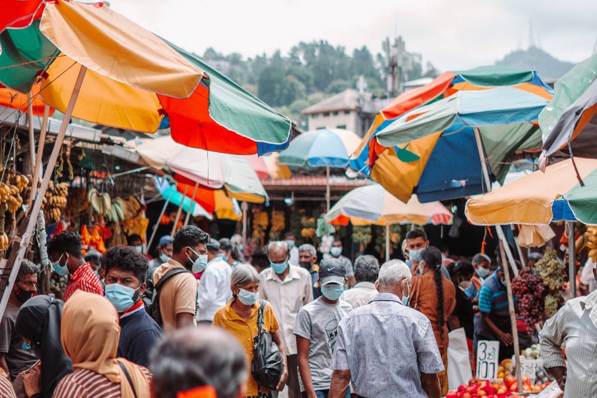 Outdoor market in Sri Lanka with colourful parsol shelters and many people wearing covid-19 face masks