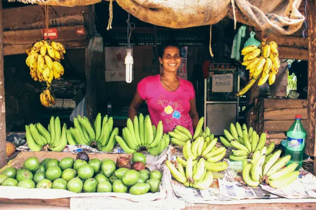 Woman stall keeper standing behind a counter of fruits
