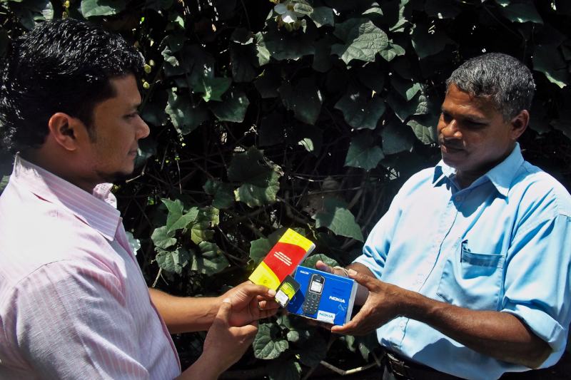 Man handling over a boxed mobile phone to a male participant