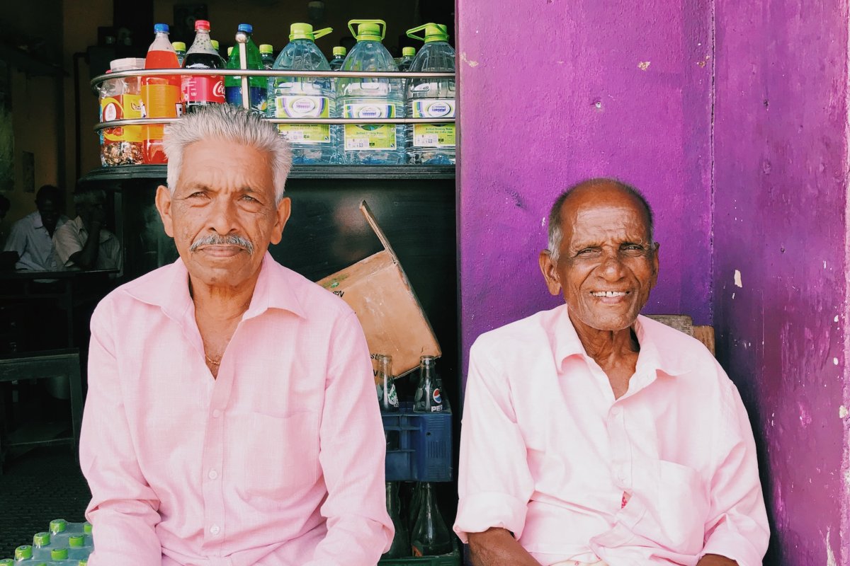 Two older Sri Lankan men sitting in front of a shop counter