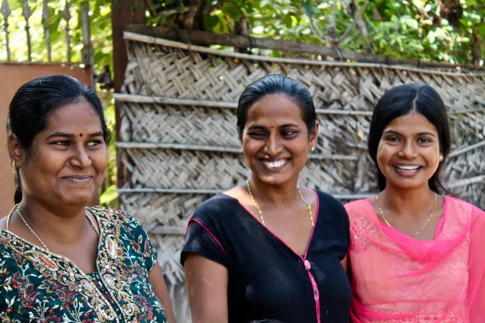 A group of three Sri Lankan women smiling towards the viewer